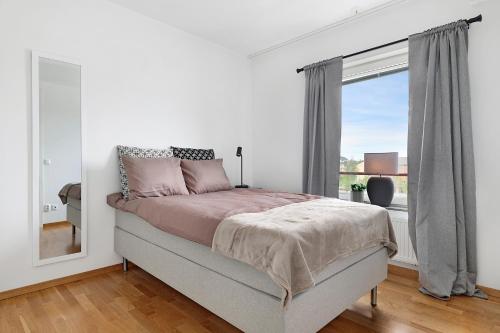 a white bedroom with a bed and a window at Guestly Homes - 3BR Modern Apartment in Piteå