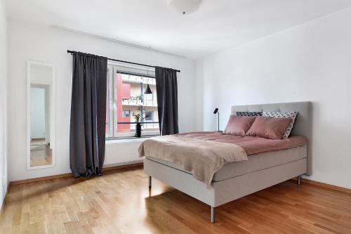 um quarto branco com uma cama e uma janela em Guestly Homes - 3BR Modern Apartment em Pitea