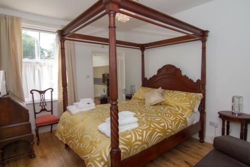 a bedroom with a canopy bed with towels on it at Abbey Canterbury in Kent