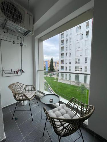 a balcony with two chairs and a table and a large window at NEW Brilant Apartment in Tirana