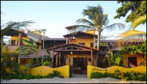 a house with palm trees in front of it at Pousada Sahara in Jericoacoara