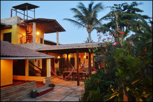 a house with a patio and a palm tree at Pousada Sahara in Jericoacoara