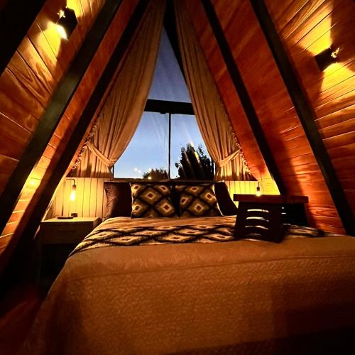 a bed in a room with a window at Chalé Alqualondë -Chácara Valfenda in São Joaquim