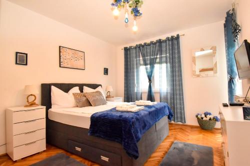 a bedroom with a bed with a blue blanket on it at Villa Kristina Rab in Supetarska Draga