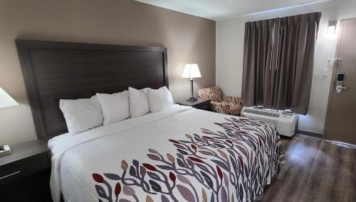 um quarto de hotel com uma cama grande e uma cadeira em Red Roof Inn & Suites Duncan em Duncan