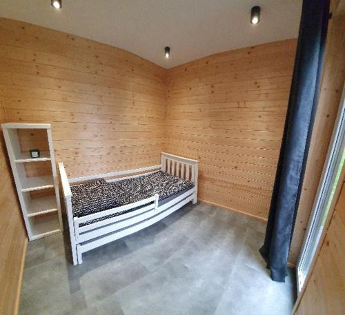 Habitación con cama en una pared de madera. en Osada Przy Młynie - Tajemnica Twojego Relaksu - W Saunie, Chacie Grillowej en Zagnańsk