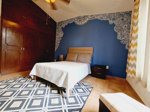 a bedroom with a bed and a blue wall at CASA LEYNA totalmente independiente, de un piso in Temixco