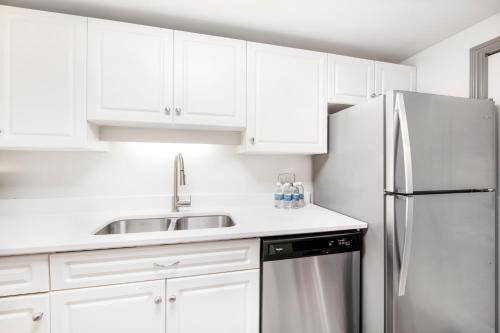 a white kitchen with a sink and a refrigerator at Victoria Regent Waterfront Hotel & Suites in Victoria