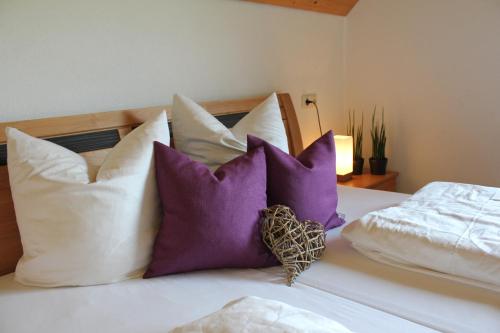 a bed with purple and white pillows on it at Apartment Magdalena in Bezau