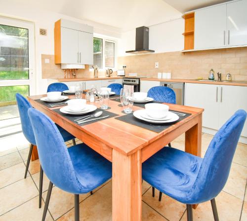 una cucina con tavolo in legno e sedie blu di Milton Keynes Modern City House a Milton Keynes