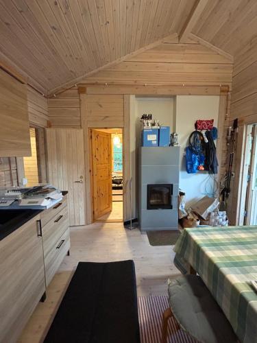 a room with a kitchen with a refrigerator and a bed at Sauna cabin in the heart of Nuuksio National Park - Mökki Nuuksiossa in Espoo