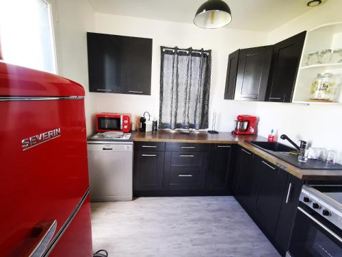 Il comprend une cuisine équipée d'un réfrigérateur rouge et de placards noirs. dans l'établissement La villa du Veillon, à Talmont-Saint-Hilaire