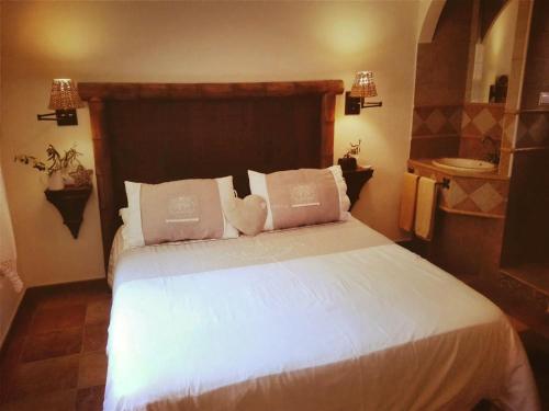 1 dormitorio con 1 cama con sábanas y almohadas blancas en Casa Rural Lares, en Casas de Don Pedro