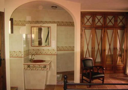 a bathroom with a sink and a chair and a mirror at Casa Rural Lares in Casas de Don Pedro