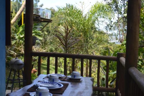 une table avec des assiettes et des tasses sur une terrasse couverte dans l'établissement a casinha, à Serra Grande
