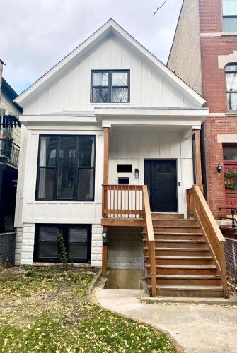 a white house with a wooden staircase in front of it at Lincoln Park Apartment with Backyard! in Chicago