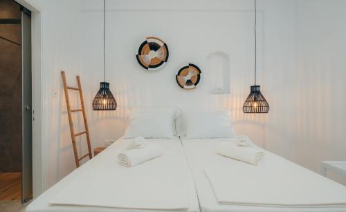 a bedroom with a white bed and two pendant lights at Nostos Sifnos in Apollonia