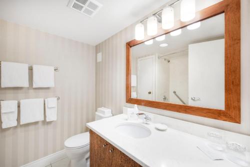 a bathroom with a sink and a mirror and a toilet at Victoria Regent Waterfront Hotel & Suites in Victoria