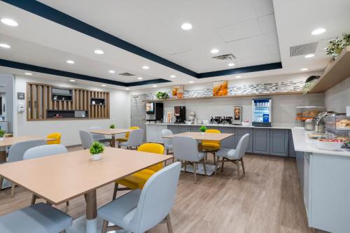 a cafeteria with tables and chairs and a kitchen at Comfort Inn & Suites Hampton near Coliseum in Hampton
