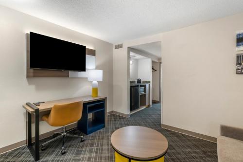 a hotel room with a desk and a tv at Comfort Inn & Suites Hampton near Coliseum in Hampton