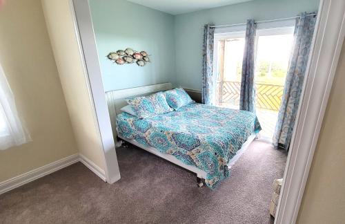 a small bedroom with a bed and a window at 8018 Beach Rd, Semi-Oceanfront, Pool/Hot Tub in Nags Head