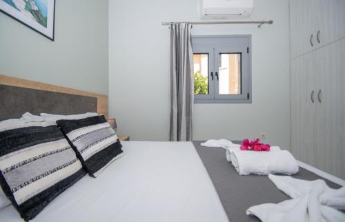 a bedroom with a white bed with black and white pillows at Liri's Apartments in Kalamaki