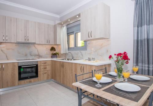 a kitchen with wooden cabinets and a wooden table and chairs at Liri's Apartments in Kalamaki