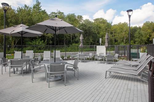 eine Terrasse mit Tischen, Stühlen und Sonnenschirmen in der Unterkunft TownePlace Suites by Marriott Orlando Airport in Orlando