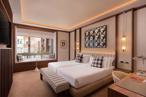 a bedroom with a bed and a couch and a window at Hotel Ercilla de Bilbao, Autograph Collection in Bilbao