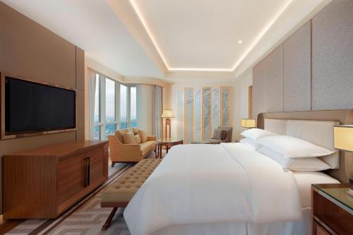 um quarto de hotel com uma cama grande e uma televisão de ecrã plano em Sheraton Petaling Jaya Hotel em Petaling Jaya