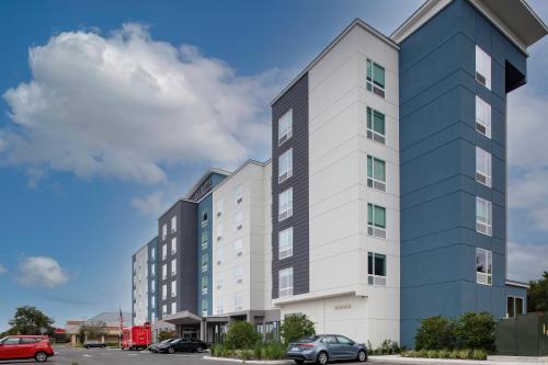 a tall building with cars parked in a parking lot at TownePlace Suites by Marriott Orlando Airport in Orlando