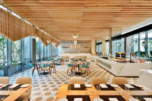 a restaurant with tables and chairs and windows at Aloft New Delhi Aerocity in New Delhi