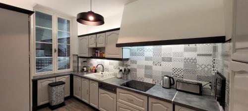 une cuisine avec des armoires blanches et un évier dans l'établissement Des Histoires d'Anges - Côté Ville - 2 meublés classés - Accueil Vélo, à Tournus