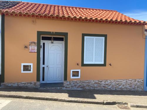 a house with a blue door and a window at Paraíso Açoreano Guest House in Achada