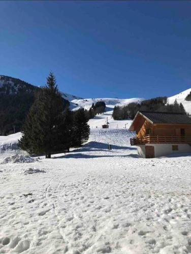 a snow covered field with a house in the background at Appartement Centre du village ALPE DU GRAND SERRE in La Morte