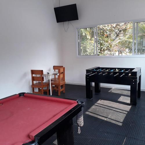 a room with a red pool table and a dining room at Recanto Vizinho do Mar in Ubatuba