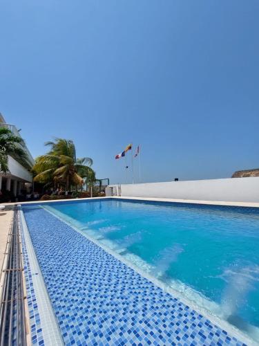 a swimming pool with blue water and palm trees at hotel 3 banderas Manzanillo del Mar in Cartagena de Indias