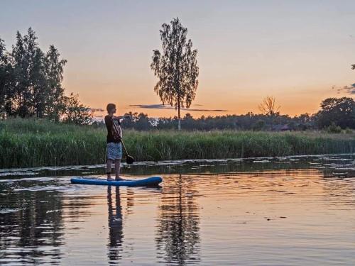 a boy is standing on a paddle board in the water at Krastmslas in Smaltāni