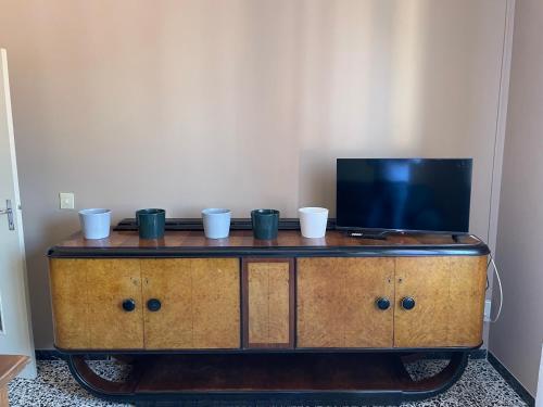 - une télévision au-dessus d'un meuble en bois avec des tasses dans l'établissement Casa Anna, à Ravenne