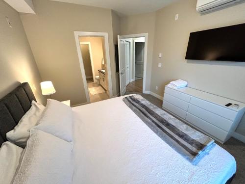 a bedroom with a white bed and a flat screen tv at Stay In The Okanagan - Copper Sky, West Kelowna in West Kelowna