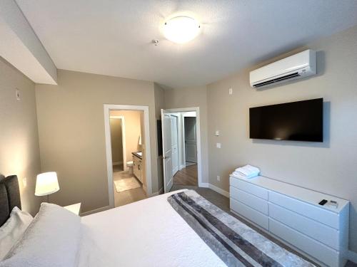 a bedroom with a bed and a flat screen tv at Stay In The Okanagan - Copper Sky, West Kelowna in West Kelowna