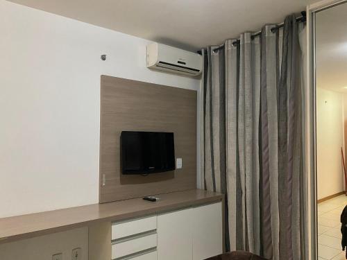 a hotel room with a tv and a curtain at Flat 309 Life beira lago in Brasilia