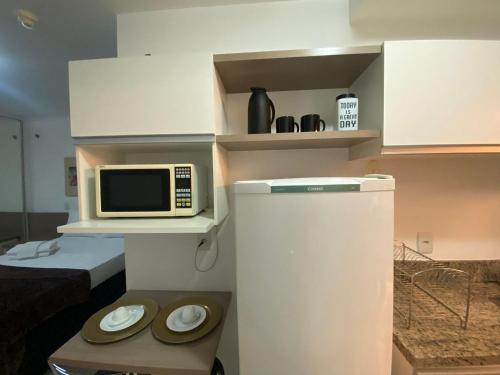 a small kitchen with a microwave and a refrigerator at Flat 309 Life beira lago in Brasilia