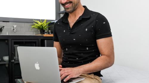 un hombre está sonriendo mientras sostiene un ordenador portátil en Monastiraki City Sleepbox- Unspoiled Athens Apartments, en Atenas