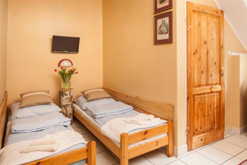 two twin beds in a room with a tv at Pensjonat Iskra in Sztum
