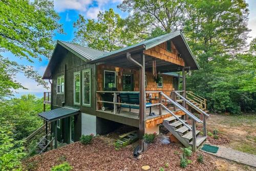 uma pequena casa na floresta com um alpendre em Updated cabin nestled on 10 acres in the woods, breathtaking Blue Ridge Mountain views em Brevard