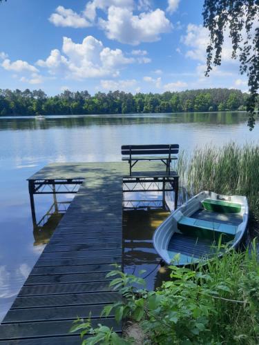 un muelle con un barco junto a un banco en un lago en Dom nad Jeziorem Bory Tucholskie Pomost 50m Łódka Kominek, en Cierplewo