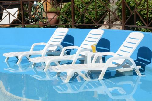 four white chairs sitting in a swimming pool at Complejo Los Cipreses in Villa Carlos Paz