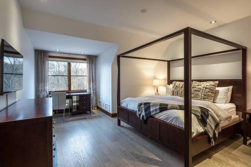 - une chambre avec un grand lit à baldaquin et un bureau dans l'établissement Étoile Du Matin 1500-5/ Tranquil Mountain Escape, à Mont-Tremblant