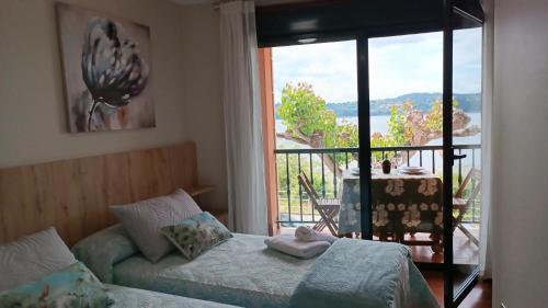 a bedroom with a bed and a balcony with a table at SALSEIRAZO - PLAYA A RIBEIRA MIÑO in Miño